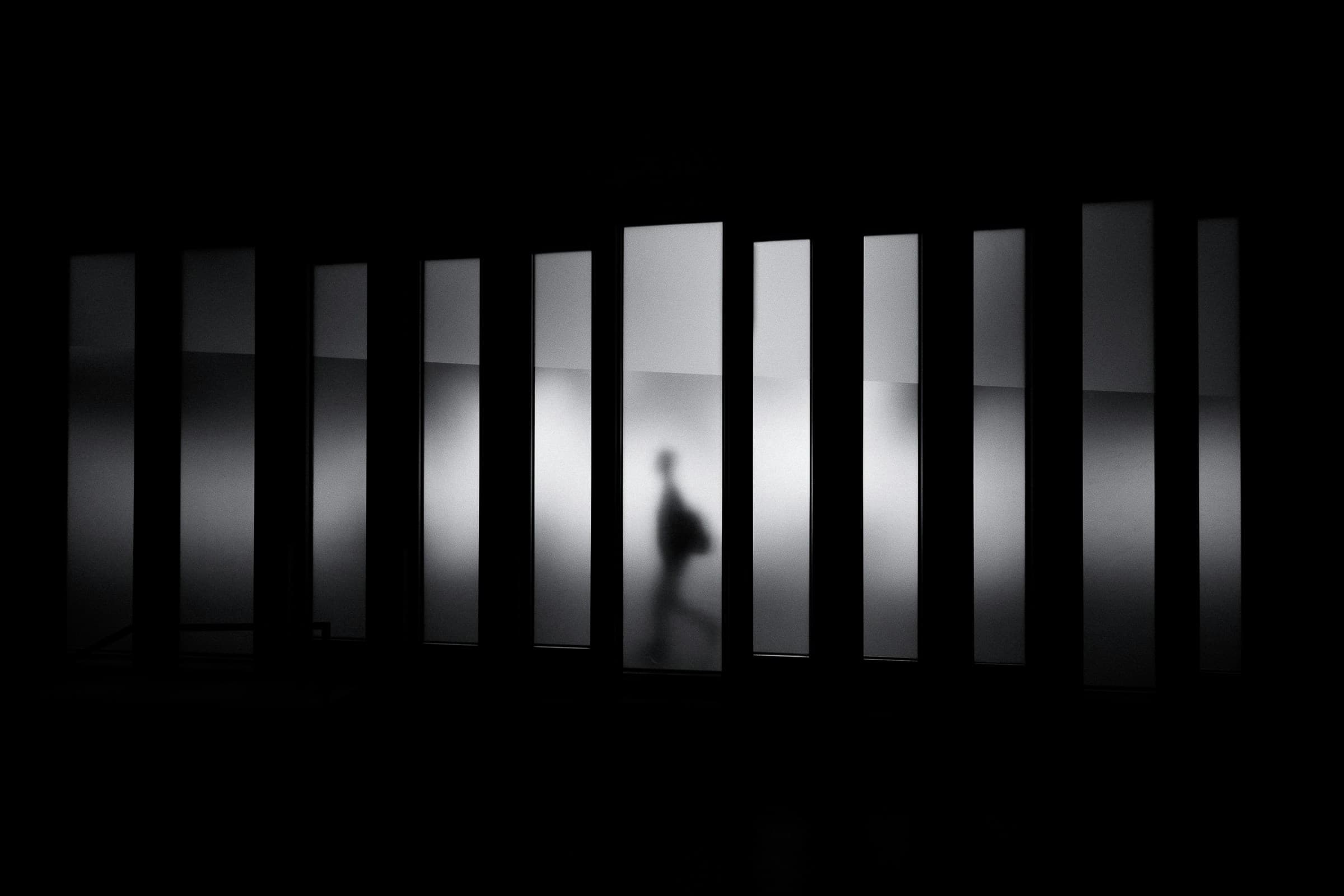 Silhouette of a person behind vertical slats of light